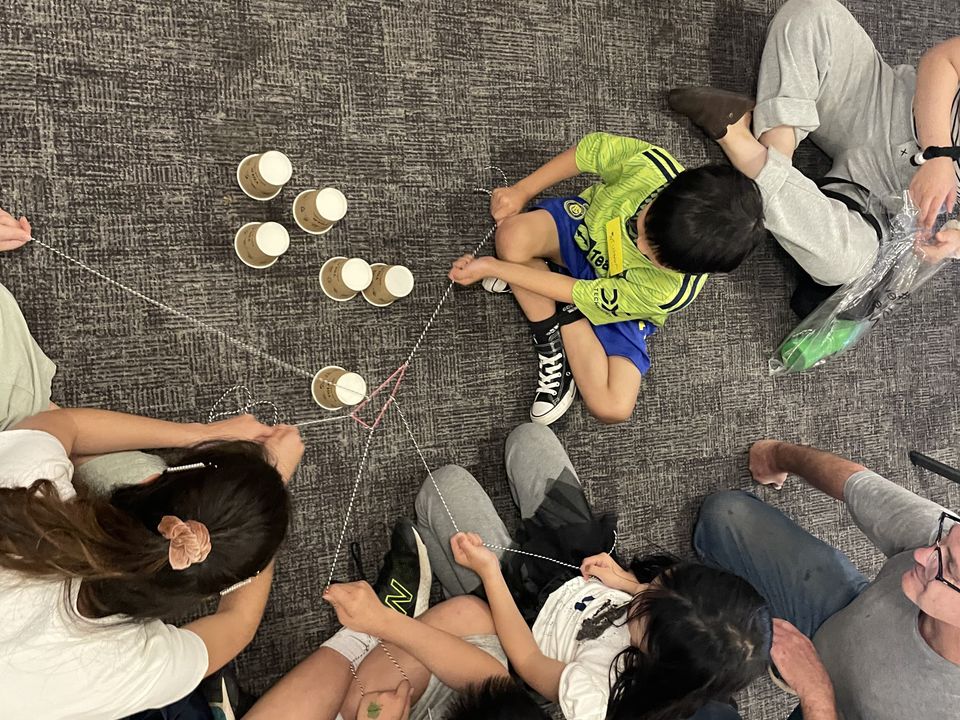 Children and adults seated in a circle for a cooperative activity