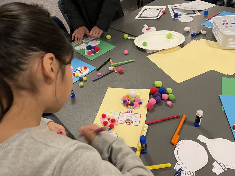 A child creating a colourful kindness craft at a community table