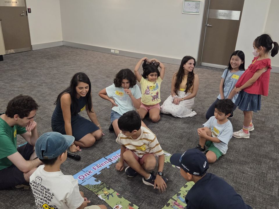 Children and adults building a friendship puzzle together